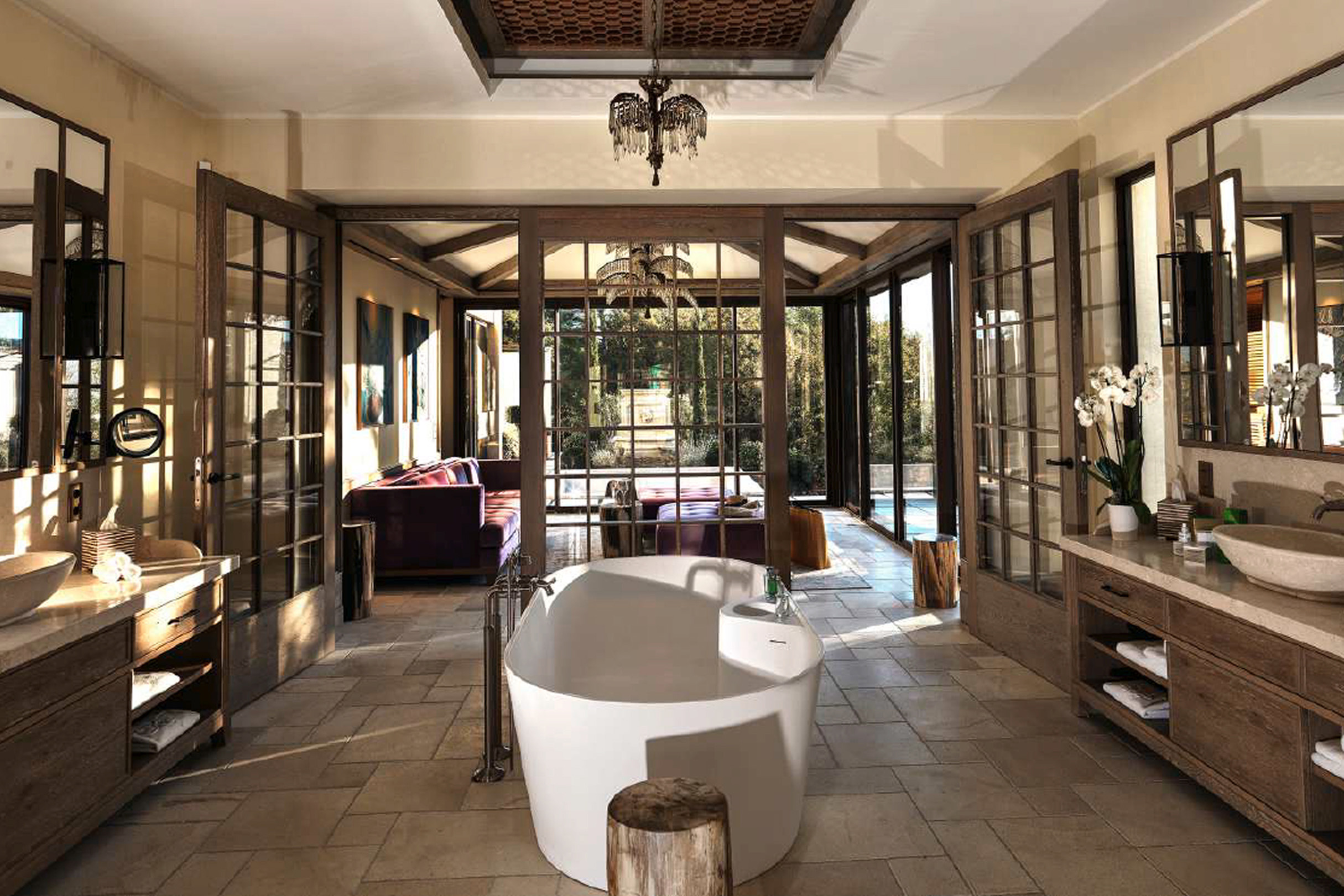 Elegantes Badezimmer mit freistehender Badewanne, großen Fenstern und Blick auf den Außenbereich von La Coquillade.