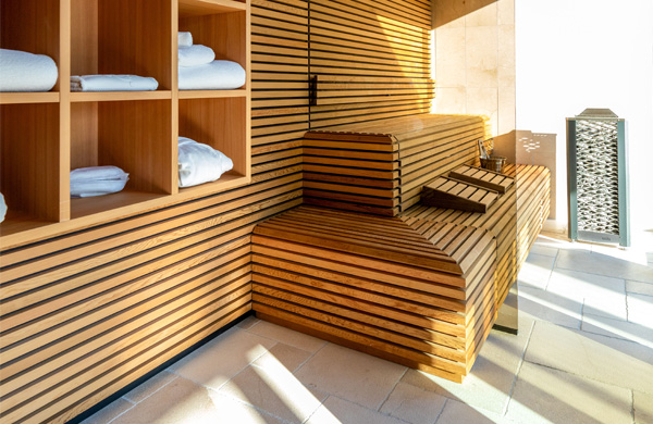 Eleganter Wellnessbereich mit Holzregalen, Handtüchern und einer stilvollen Liegefläche für Entspannung.