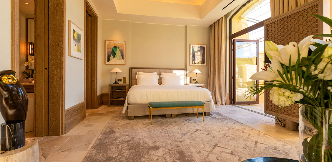 Elegantes Schlafzimmer in La Coquillade mit modernem Design, Kunstwerken und Blick auf die Terrasse.