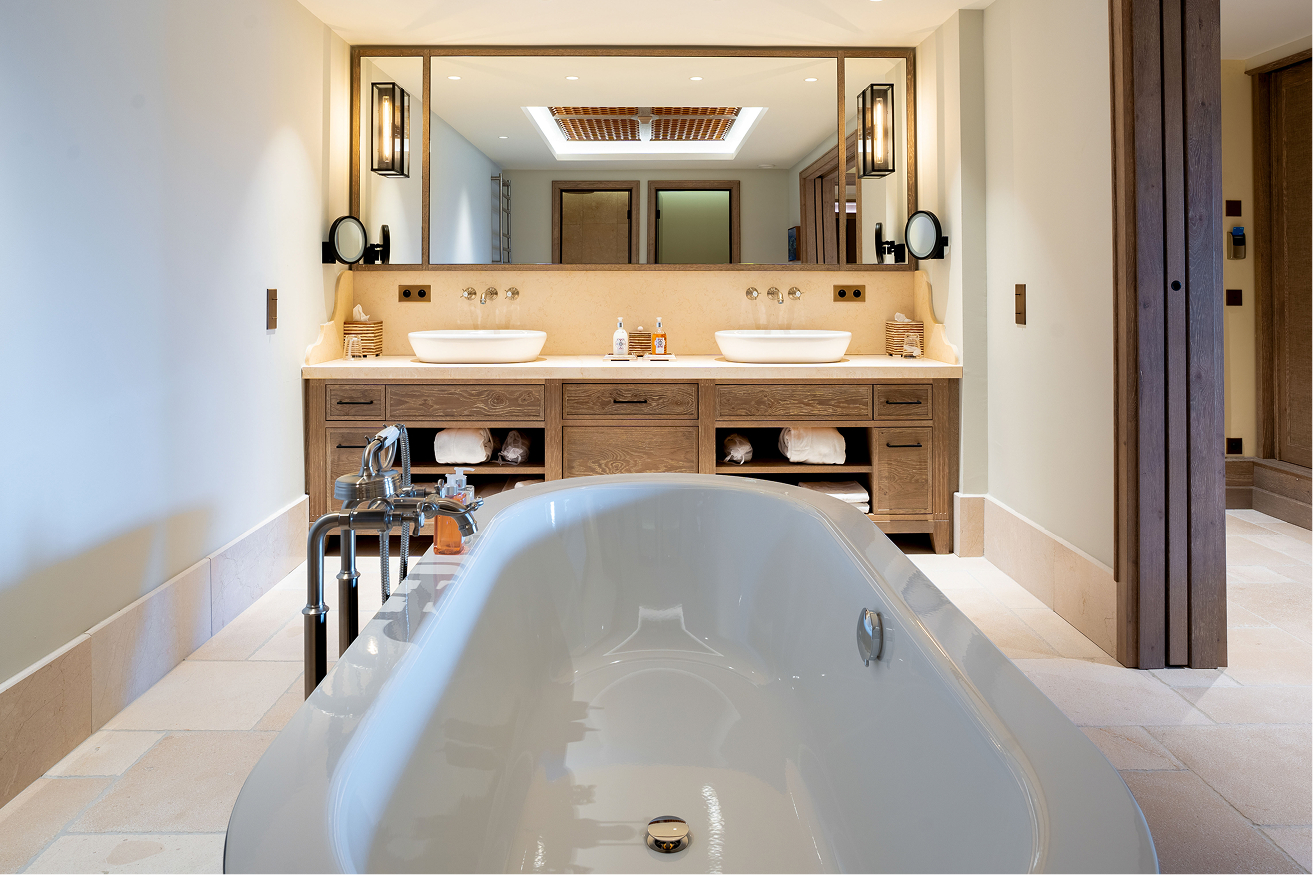 Elegantes Badezimmer mit freistehender Badewanne, Doppelwaschtisch und stilvollen Holzdetails.