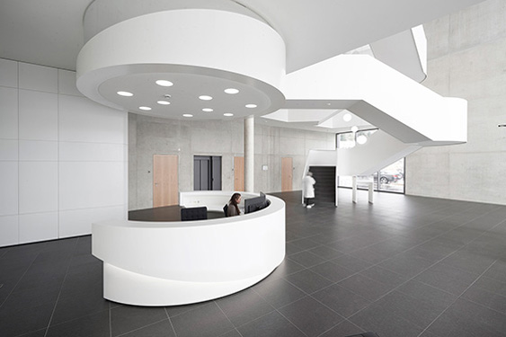 Moderne Empfangshalle mit geschwungener Theke, hellem Licht und minimalistischer Architektur bei Storz & Bickel.