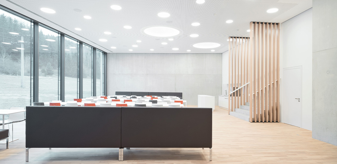 Moderne, helle Innenansicht eines Empfangsbereichs mit Sitzgelegenheiten und Holztreppe bei Storz & Bickel.