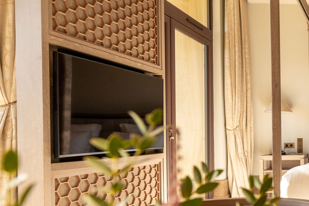 Elegantes Hotelzimmer mit einem Fernseher, Holzverkleidung und sanften Farben für eine entspannende Atmosphäre.