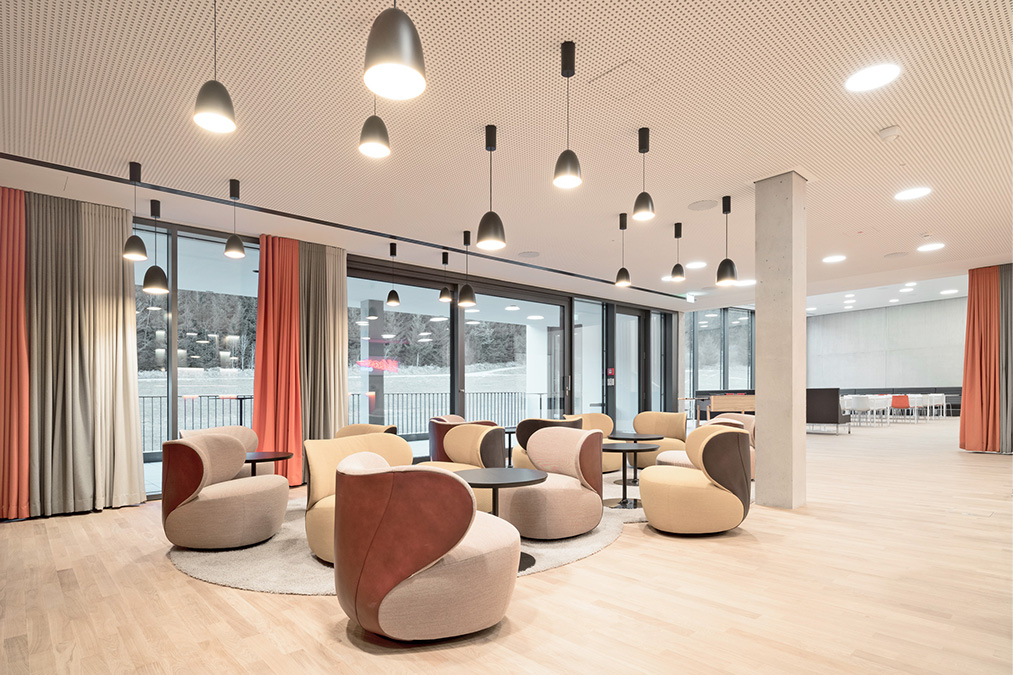 Moderne Lounge mit stilvollen Sesseln, Tischen und großen Fenstern, die einen Blick auf die Natur bieten.