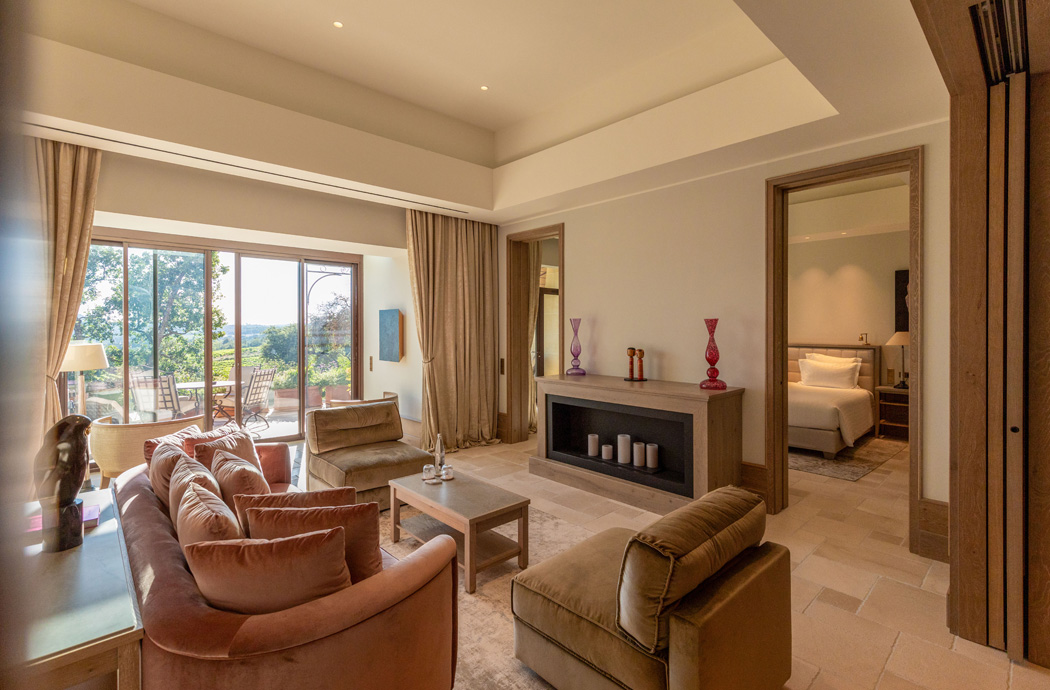 Elegantes Wohnzimmer mit Blick auf die Landschaft, stilvollen Möbeln und Zugang zu einer Terrasse.