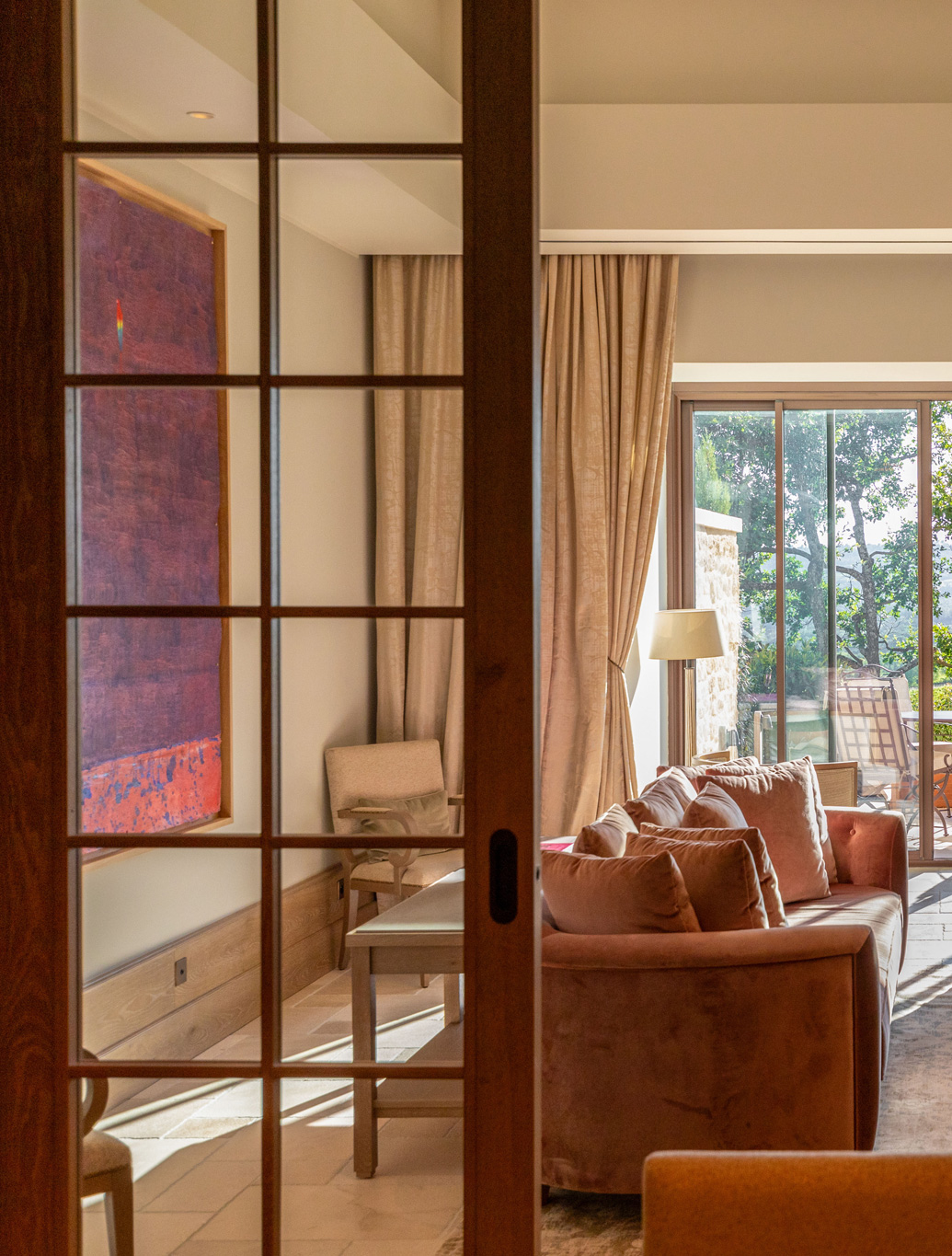 Elegantes Wohnzimmer mit großen Fenstern, gemütlicher Couch und Blick auf die Terrasse in La Coquillade.