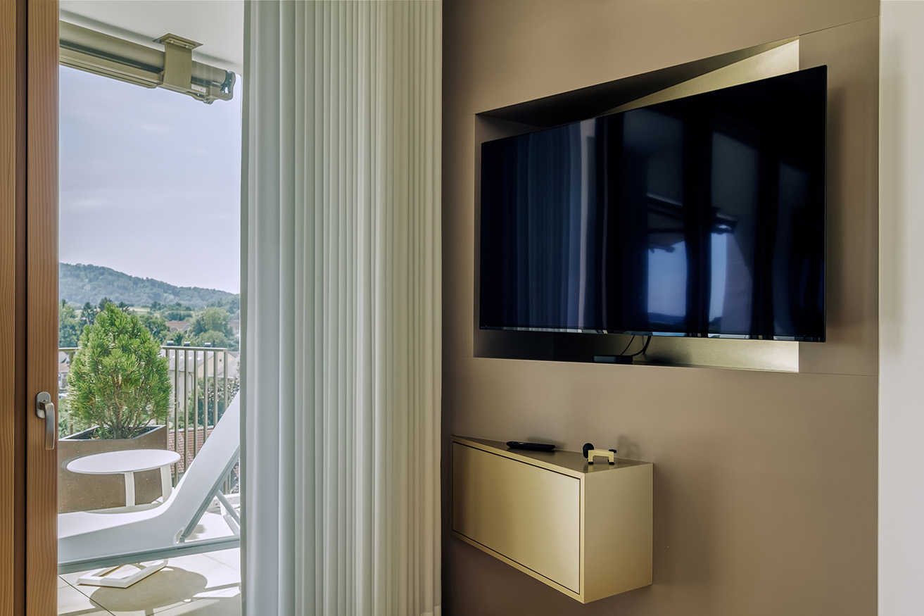 Moderne Wohnräume mit einem Fernseher und Blick auf den Balkon in einem Privathaus in Süddeutschland.