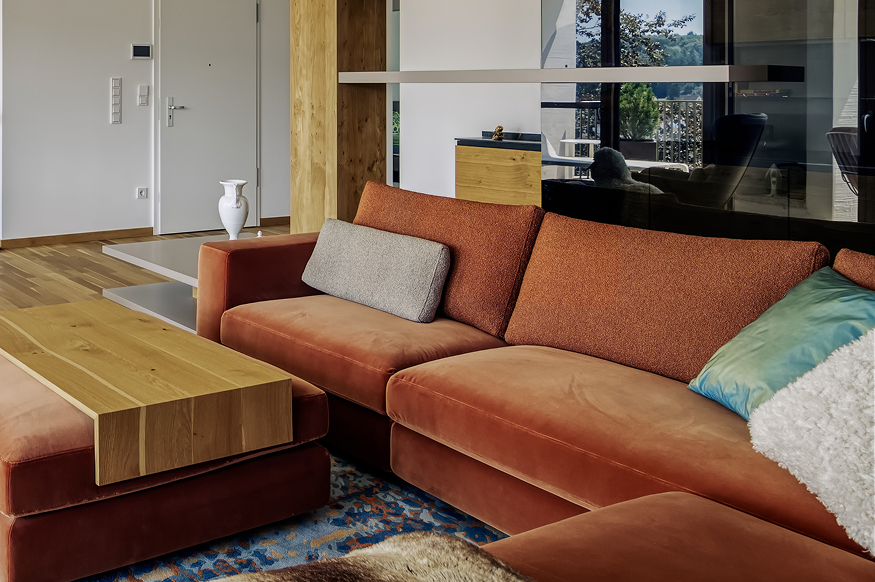 Gemütliches Wohnzimmer mit orangefarbenem Sofa, Holztisch und modernen Akzenten in einem Privathaus in Süddeutschland.